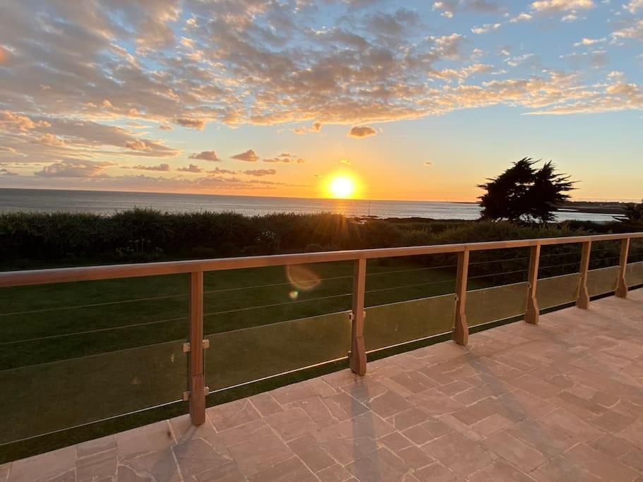 - un coucher de soleil sur l'océan avec une clôture en bois dans l'établissement 