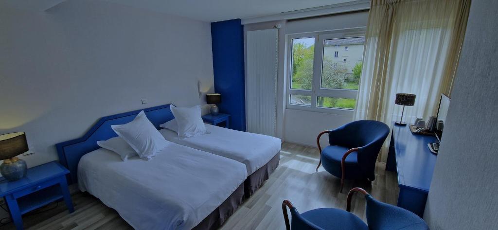 a blue room with a bed and a chair and a window at Beau Rivage in Charavines