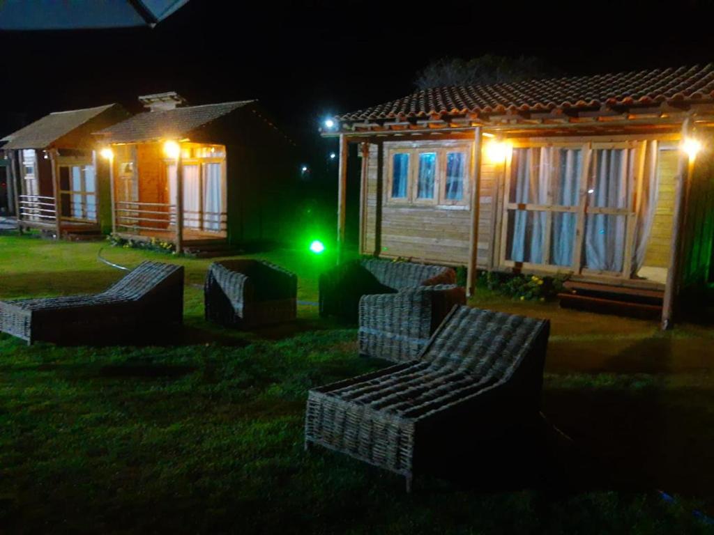 un grupo de sillas frente a una cabaña por la noche en La Belle de Jour, en Majorlândia