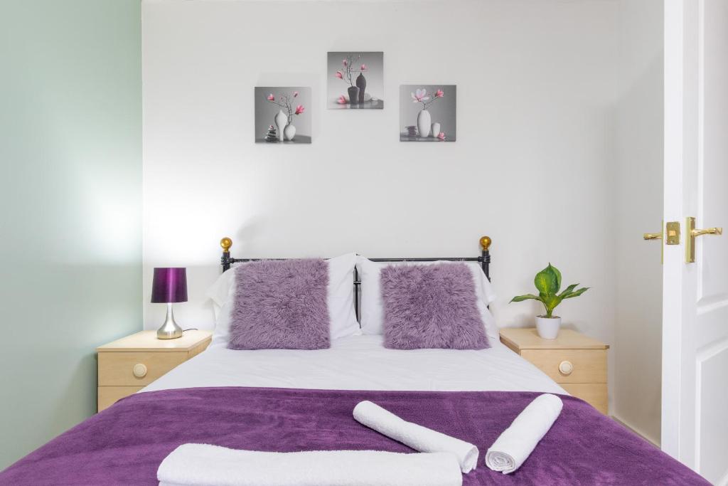 a bedroom with a purple bed with two white towels on it at Newly refurbed, 5BR, Sleeps 12 in Northampton