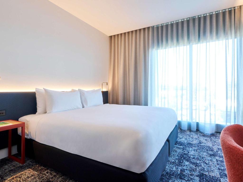 a hotel room with a large bed and a window at ibis Styles Melbourne Airport in Melbourne
