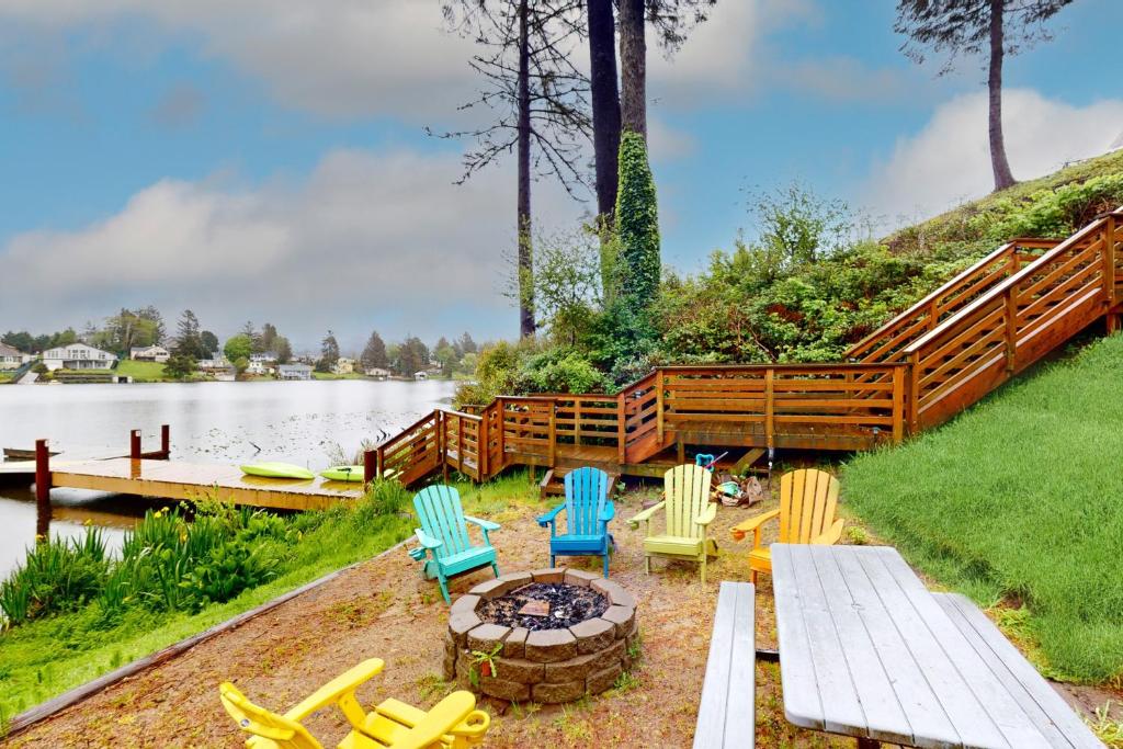 a group of chairs and a fire pit next to a lake at Lazy Lookout on Devils Lake in Lincoln City