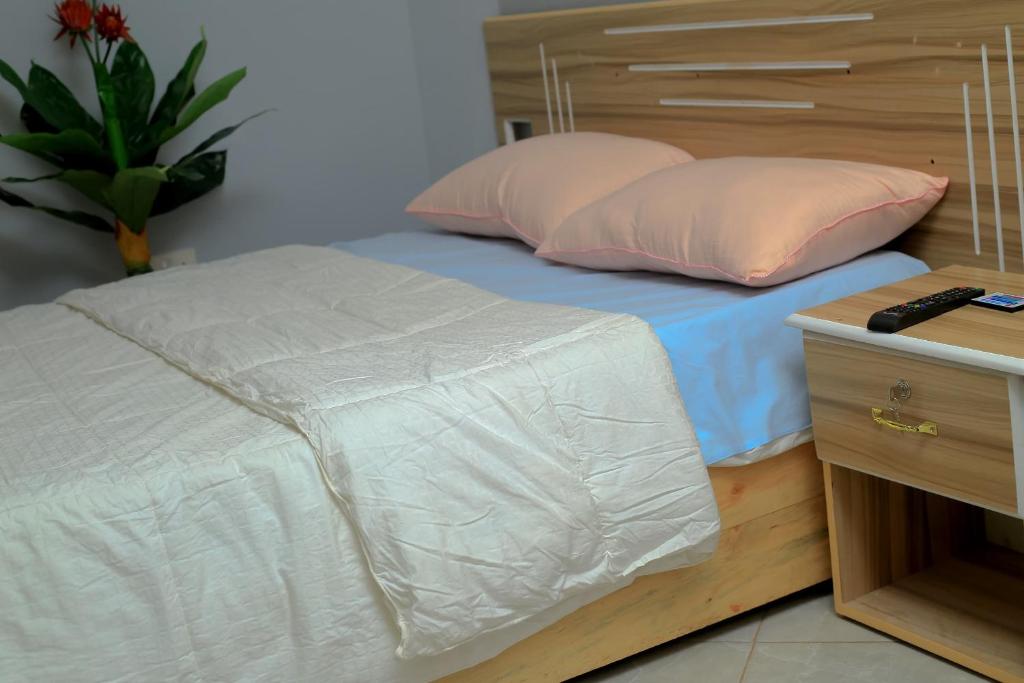 a bed with two pillows and a wooden head board at EQUATOR GATES HOTEL Bulega in Bulenga