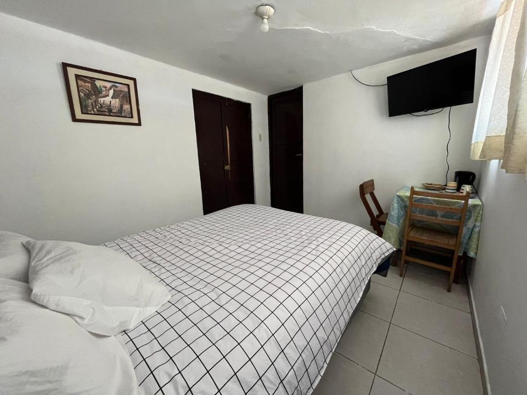 a bedroom with a bed and a table and a television at Qosqollay Plaza de armas in Cusco