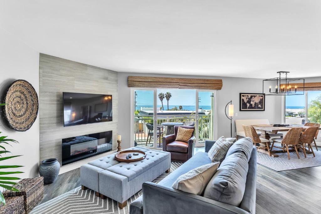 ein Wohnzimmer mit einem Sofa, einem TV und einem Tisch in der Unterkunft Ocean Views & Sounds - Bird Rock in San Diego