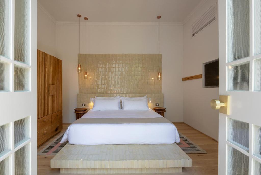 a bedroom with a large white bed and two tables at Hotel Casa Cuenca in Mexico City