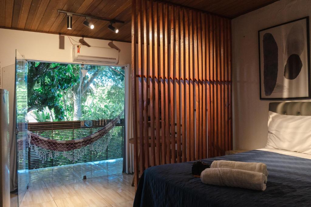ein Schlafzimmer mit einem Bett und ein Fenster mit einer Hängematte in der Unterkunft Apartamento Pituba Jardim in Itacaré