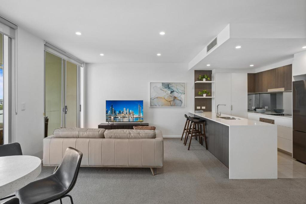 a kitchen and living room with a couch and a table at Sleek 2-Bed with Balcony and Communal BBQ Area in Brisbane