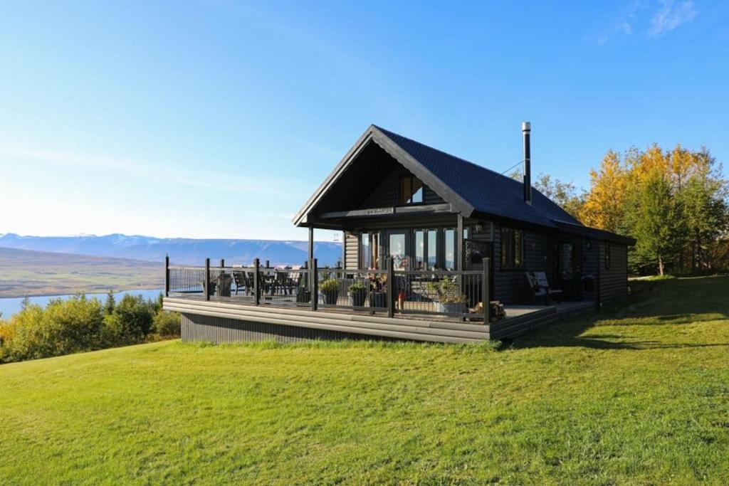 a house on top of a hill with a green field at Charming Cabin close to Akureyri in Halllandsnes