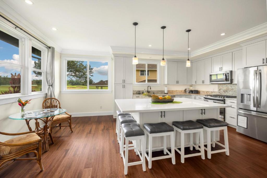 a kitchen with white cabinets and a large island with bar stools at Kolepa Kai in Koloa