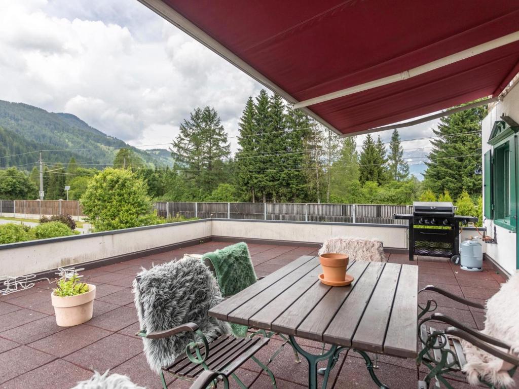 un patio con mesa de madera, sillas y parrilla en Chalet one, en Kitzbühel