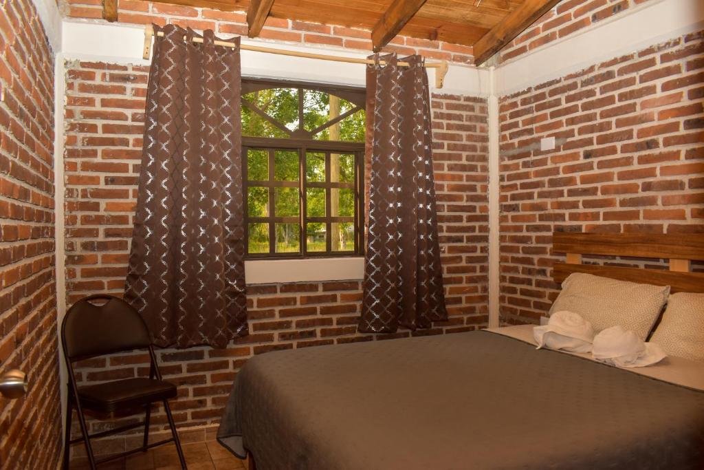 a brick room with a bed and a window at Cabañas De la Vega in Zacatlán