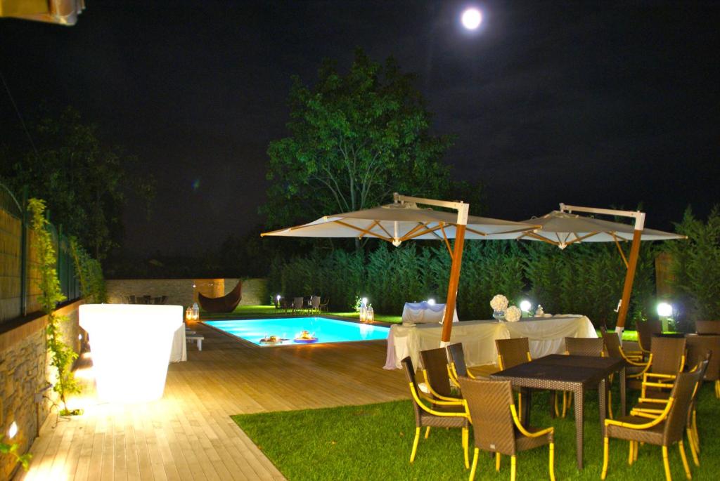 un patio con mesas, sombrillas y una piscina en Locanda Ristorante Gavarini en Bagnone
