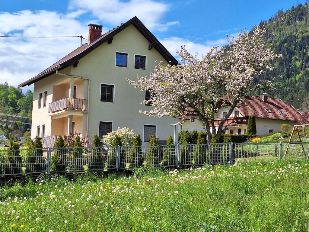 Holiday home in the ski area in Kötschach-Mauthen في Laas: بيت ابيض به سياج وشجر مزهر