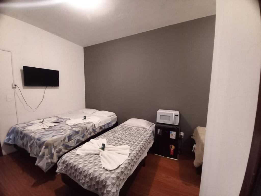 a room with two beds and a flat screen tv at Lofts Visconde in Joinville