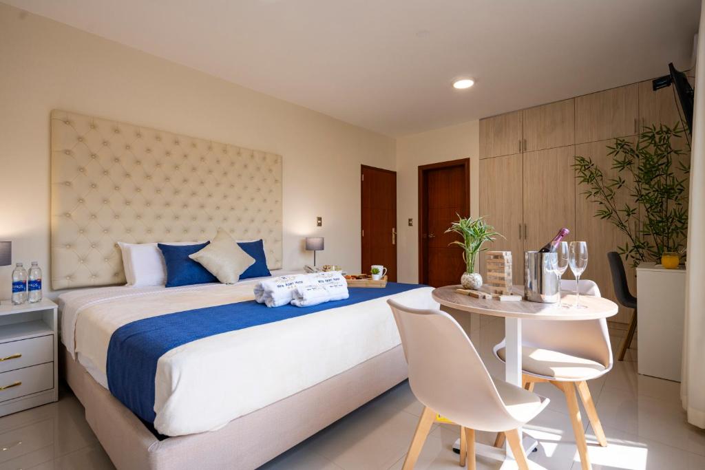 Rits Apart Hotel في ليما: غرفة نوم بسرير كبير وطاولة مع كراسي