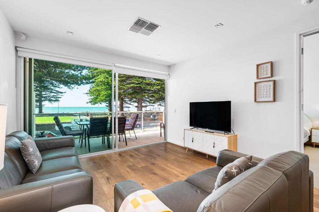 sala de estar con sofá y TV en Luxury Breeze Beachfront Apartment, en Victor Harbor