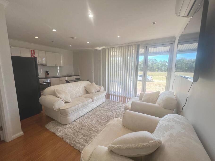 a living room with two white couches and a kitchen at Home away from home! in Dubbo
