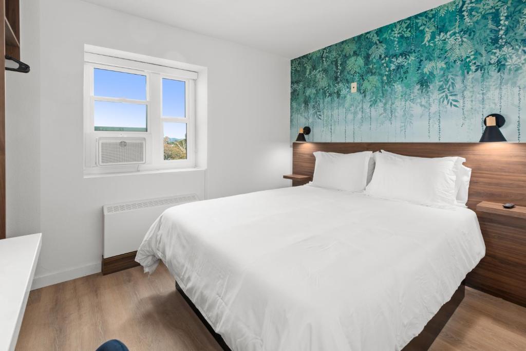 Un dormitorio con una gran cama blanca y una ventana en Uptown Inn by Vantaggio Suites en San Diego