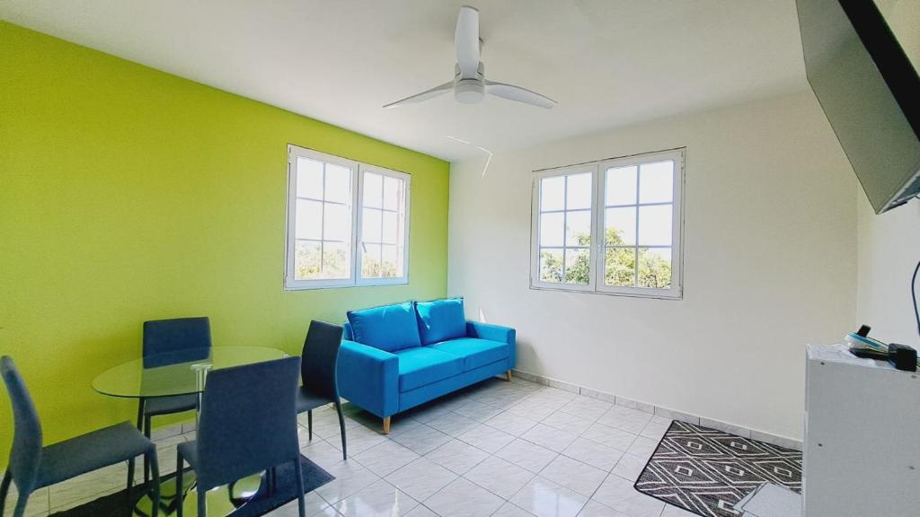 un salon avec une chaise bleue et une table dans l'établissement La Baie de Coreil, à Bouillante