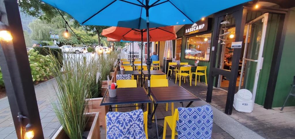 a restaurant with tables and chairs and an umbrella at Harrison Spa Motel in Harrison Hot Springs