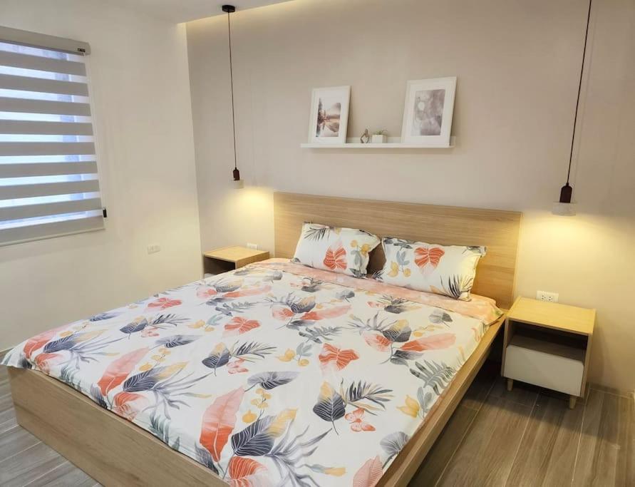a bedroom with a bed with a floral bedspread at Kiddie Hostel Unit 30B-kids and pets friendly in Subic bay freeport zone in Kababae