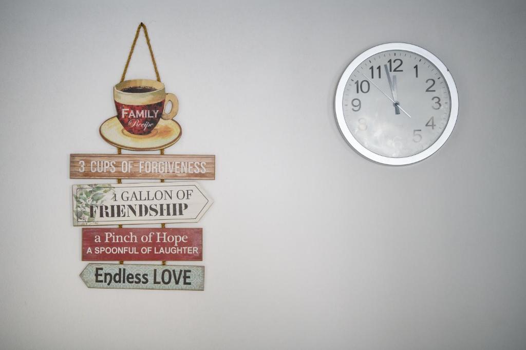 une horloge et un panneau avec une tasse de café dans l'établissement Olympia Apartment 2, à Larnaka