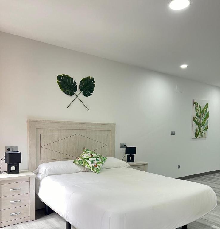 Un dormitorio con una cama blanca con hojas en la pared en Rosal Central Studios, en Oviedo
