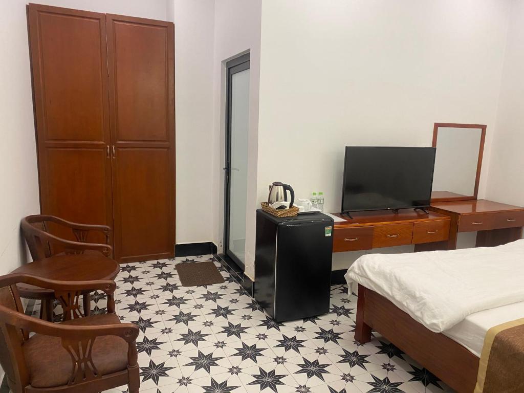 een slaapkamer met een bed, een televisie en een dressoir bij Khách Sạn Phụng Vy in Ap Rạch Soi