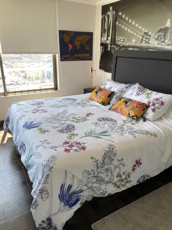 a bedroom with a bed with a floral comforter at Depto frente a Playa con hermosa vista al mar Condominio Mar Egeo in Iquique