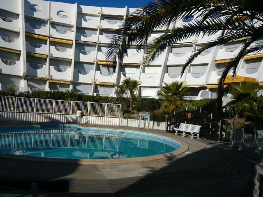 une piscine en face d'un grand bâtiment dans l'établissement Villa La Grande-Motte, 3 pièces, 6 personnes - FR-1-328-222, à La Grande Motte