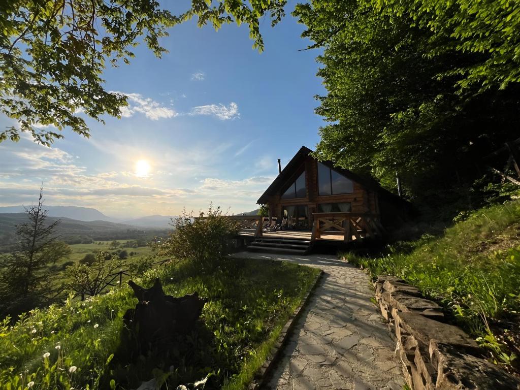 una cabaña en una colina con el sol en el cielo en Green Cottage, en Râșnov