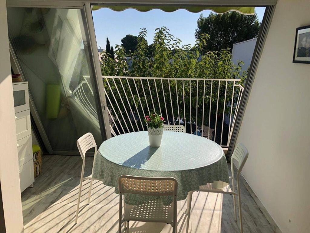 d'une table avec des chaises et un vase de fleurs sur le balcon. dans l'établissement Charmant T2 Alcôve Est à 600m Plage, Parking, WIFI, Quartier Calme - FR-1-328-258, à La Grande Motte