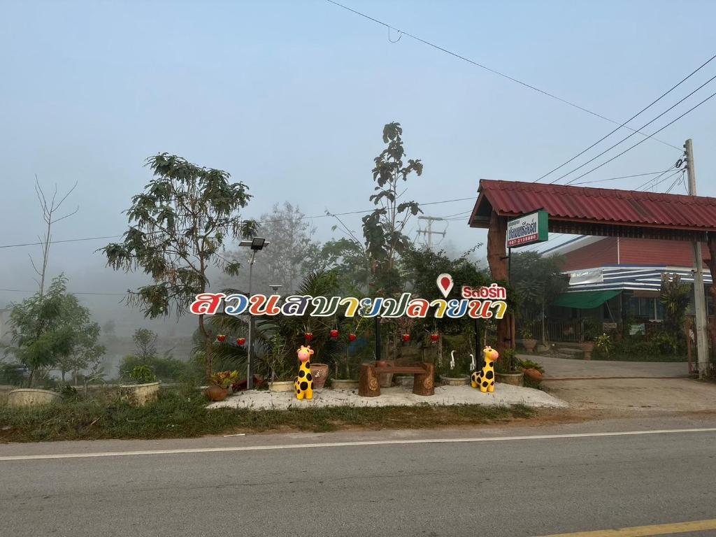 una gasolinera con señales a un lado de la carretera en สวนสบายปลายนารีสอร์ท en Ban Hin Lat