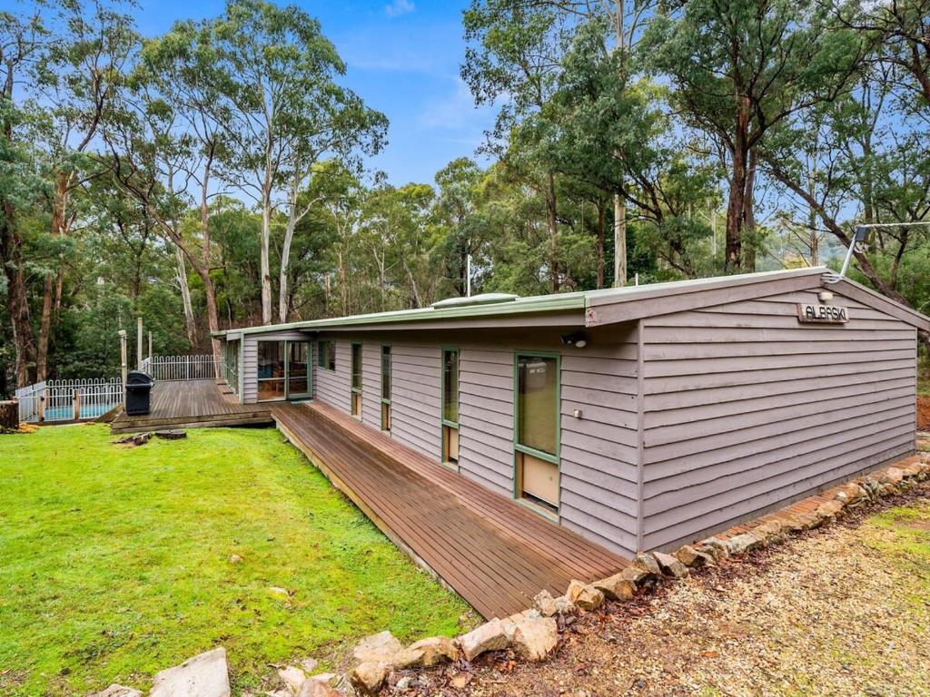 a small house with a wooden deck in a yard at Albaski Lodge- Room 4 in Mount Buller