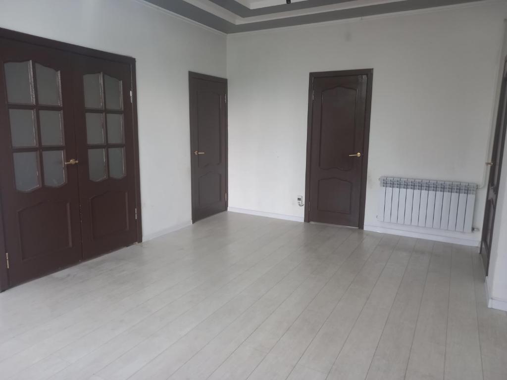 an empty room with brown doors and white walls at Zholaman in Kerben