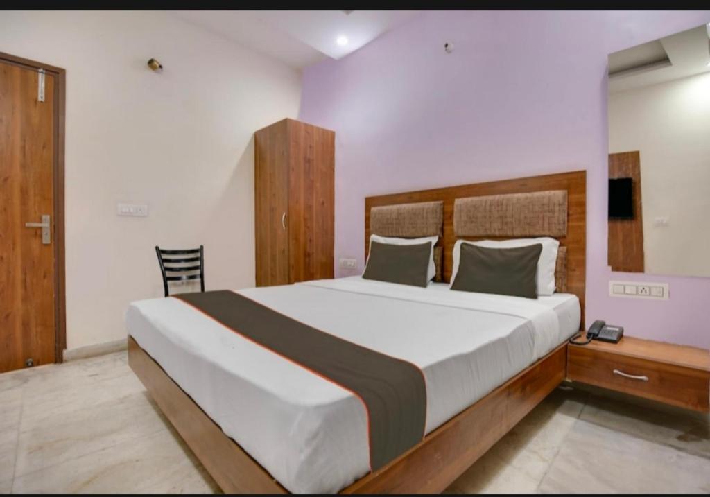 Schlafzimmer mit einem großen Bett mit einem Kopfteil aus Holz in der Unterkunft Hotel deep bell hotel in Chandīgarh