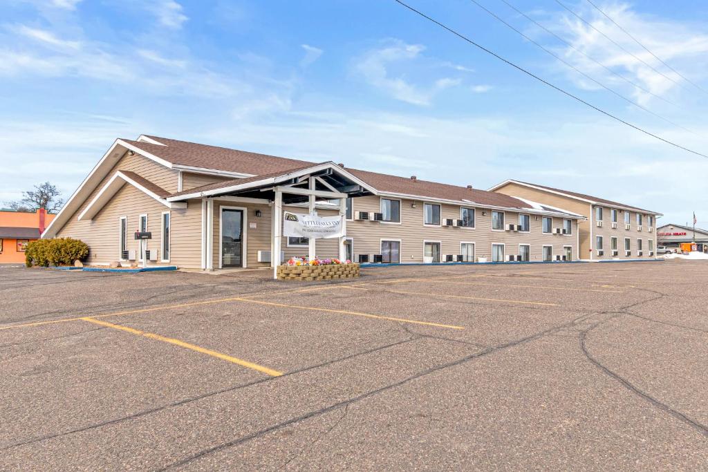 Un gran edificio con un estacionamiento enfrente. en StayInn Little Falls, en Little Falls