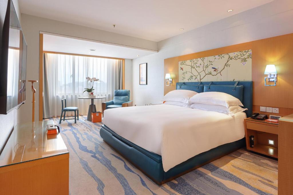 廈門市にある厦門 エアラインズ レイクサイド ホテルの大きなベッドとテーブルが備わるホテルルームです。
