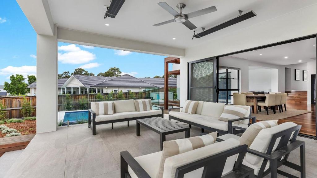 a living room with white furniture and a patio at Villa Tallawanta in Pokolbin