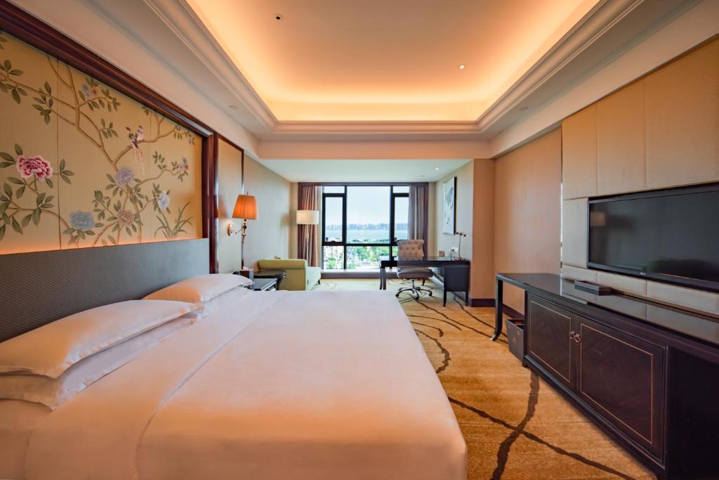a hotel room with a large bed and a flat screen tv at Sheraton Shantou Hotel in Shantou