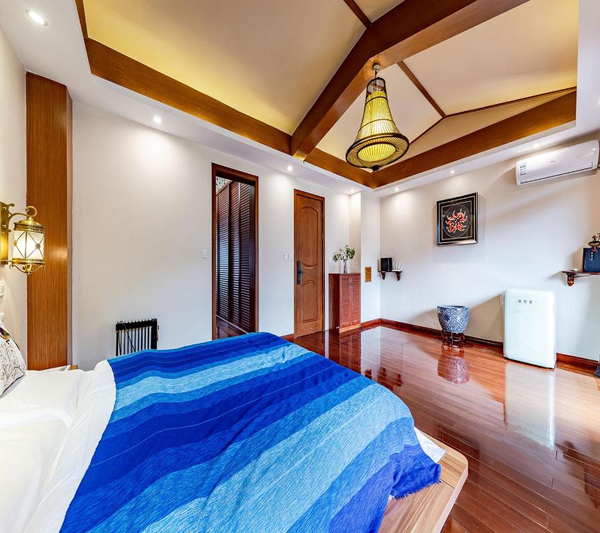 sypialnia z dużym łóżkiem i niebieskim kocem w obiekcie Annie Dianchi Lake Villas w mieście Kunming