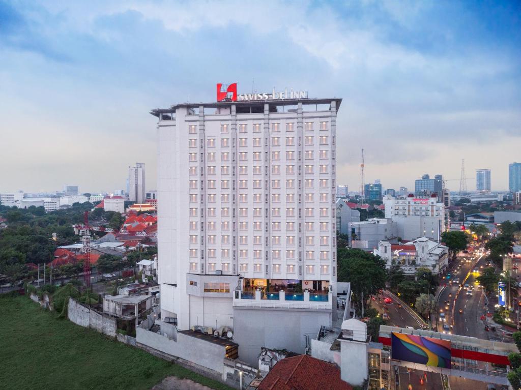 a large white building with a sign on top of it at Swiss-Belinn Tunjungan Surabaya in Surabaya