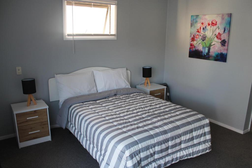 a bedroom with a bed and two night stands with two lamps at Aqua Apartment in Napier