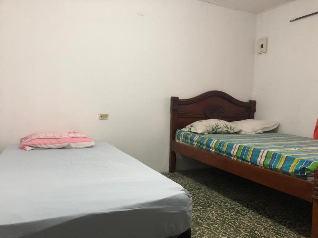 2 Betten in einem Zimmer mit weißen Wänden in der Unterkunft Hostal Los Abuelos Colombianos in Cartagena de Indias