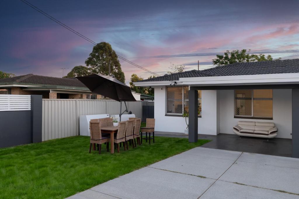 a backyard with a table and chairs and an umbrella at 2B cozy house near the airport in Perth