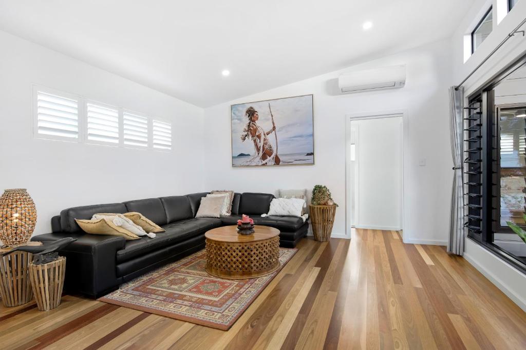 ein Wohnzimmer mit einem schwarzen Sofa und einem Tisch in der Unterkunft Elvis on Brodie - luxury boutique accommodation in Coffs Harbour