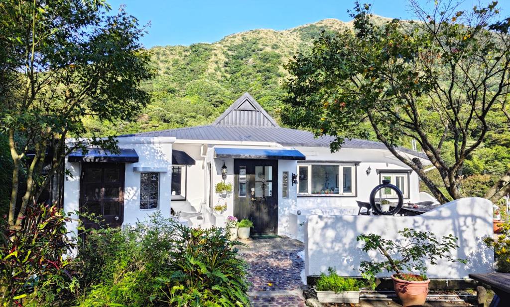 una casa bianca con una montagna sullo sfondo di 金石新月光 a Jiufen