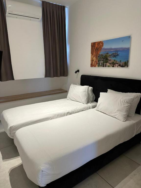 two beds in a hotel room with white sheets at Sun Sea Center in Eilat