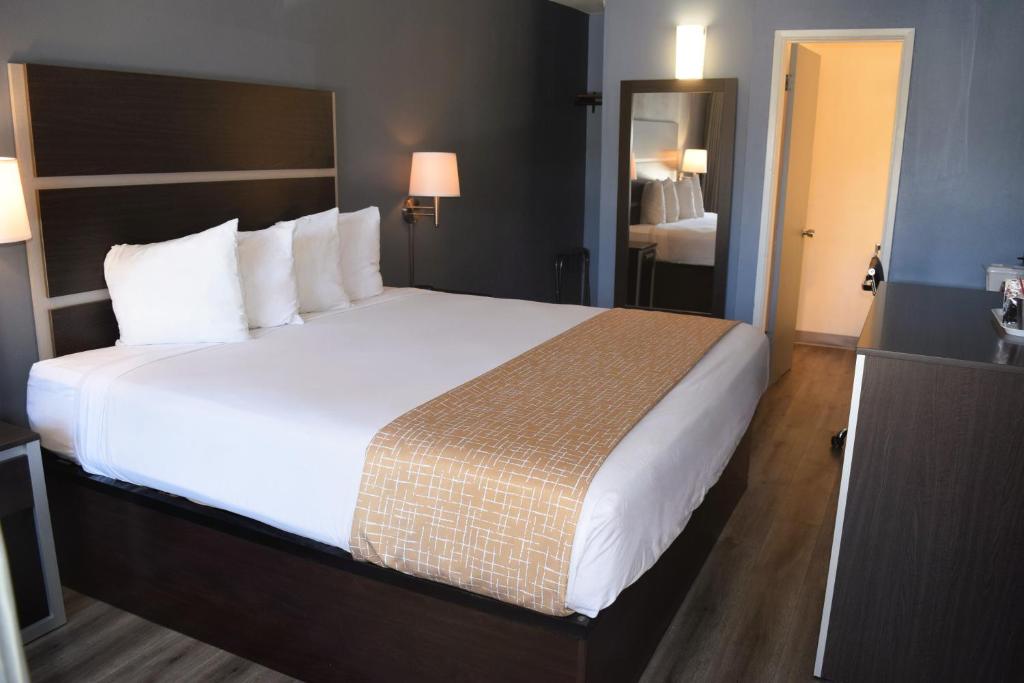 a hotel room with a large bed with white sheets at SF Central Hotel in San Francisco